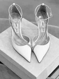 a pair of white high heel shoes sitting on top of a box