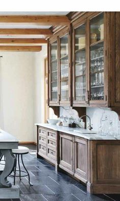 a kitchen with wooden cabinets and marble counter tops, along with black tile flooring