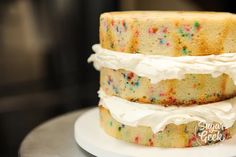 a three layer cake with white frosting and sprinkles on the top