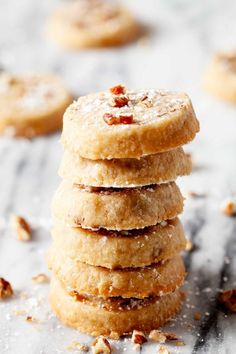 a stack of cookies sitting on top of a table covered in powdered sugar and nuts