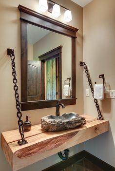 a bathroom sink sitting under a mirror next to a chain hanging on the wall above it