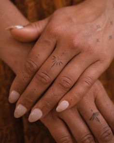 two people holding hands with tattoos on their fingers and one has a star tattoo on the ring finger