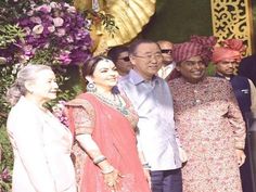 a group of people standing next to each other in front of a flower covered wall