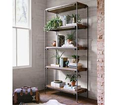 a metal shelf with plants and books on it next to a window in a room