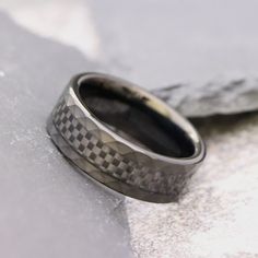 a wedding band with a checkered pattern on it is sitting on the snow covered ground