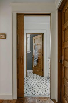 an open door leading into a bathroom with wood floors and white walls on either side