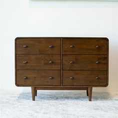 a wooden dresser sitting on top of a carpeted floor next to a white wall