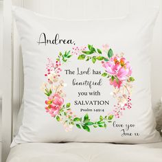 a white pillow with pink flowers and bible verse on the front, sitting on a chair