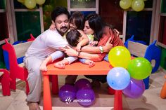 a family sitting at a table surrounded by balloons