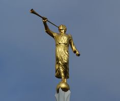 a golden statue holding a baseball bat on top of a building