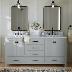 two sinks and mirrors in a bathroom with rugs on the floor next to them