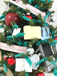 a christmas tree decorated with green ribbon and red apples on it's top is surrounded by other items