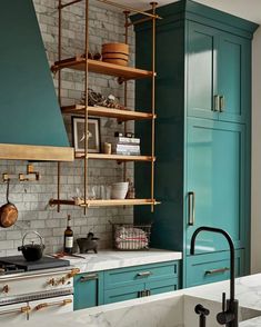 a kitchen with blue cabinets and white marble counter tops, an open shelving unit above the stove