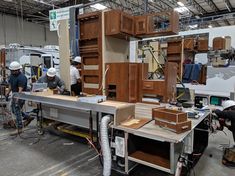 workers working on cabinets in a factory with lots of woodwork tools and equipment around them