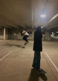 two people are skateboarding in an empty parking garage