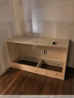 an unfinished entertainment center in the corner of a room with hard wood flooring and white walls