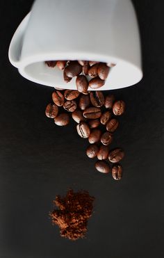 coffee beans and ground cinnamon on a black surface with a white light fixture in the background