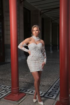 a woman in a short white dress posing for the camera with her hands on her hips