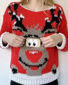 a woman is holding a camera in front of her face and wearing a reindeer sweater