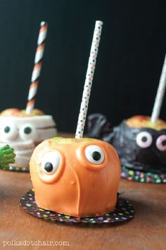 three halloween cake pops with googly eyes and candy sticks in the shape of pumpkins