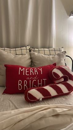 a red and white pillow on top of a bed next to a pair of slippers