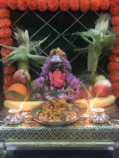 an arrangement of fruits and vegetables on a table with a buddha statue in the background