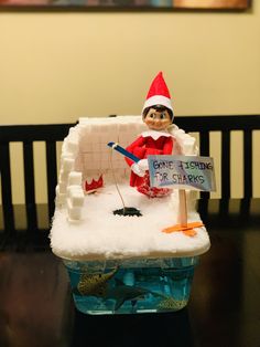 an elf is sitting on top of a fake ice block with a sign that says gone fishing for shark