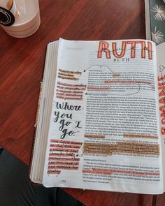 an open book with writing on it sitting on a table next to a coffee cup