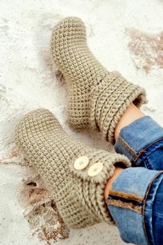 someone wearing knitted slippers with buttons on the bottom and one button at the top