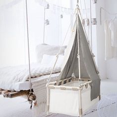 a white bed with a gray tent hanging from it's side