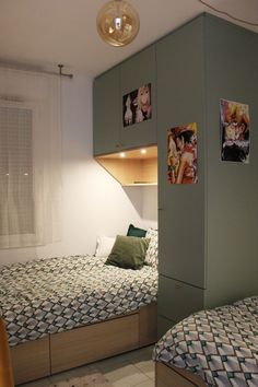 two beds in a small room with pictures on the wall above them and below them