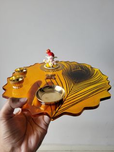 a person is holding a small tray with two cups on it and an object in the middle