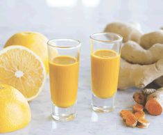 two glasses filled with orange juice next to carrots