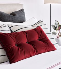 a bed with red pillows and white sheets