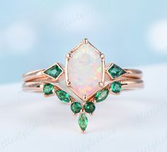 an opal and emerald ring on a white surface