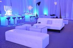 white couches and stools in a room with blue lighting