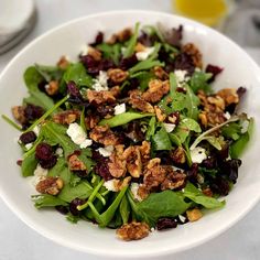 a white bowl filled with spinach and cranberries on top of a table