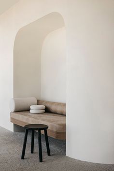 a couch and table in a room with arches on the wall above it, along with two stools