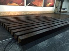 there is a large wooden slatted bed in the middle of an empty room