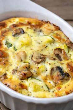 a casserole dish with mushrooms, cheese and broccoli in it on a wooden table