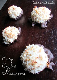 four cookies with chocolate frosting and coconut toppings on a wooden surface, ready to be eaten