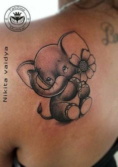 an elephant tattoo on the back of a woman's upper arm, with a flower in its trunk