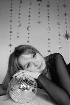 a woman laying on the floor with a disco ball in front of her and stars hanging from the ceiling behind her