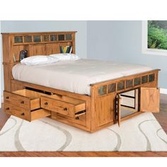 a wooden bed with drawers underneath it in a room next to a carpeted floor