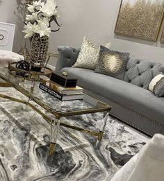 a living room with gray couches and white flowers on the coffee table in front of it