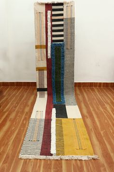 a multicolored area rug on the floor with wooden floors and white walls in the background