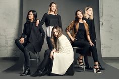 five women sitting on chairs in front of a wall