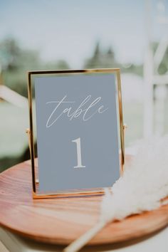 a table number sitting on top of a wooden plate next to a white feathery