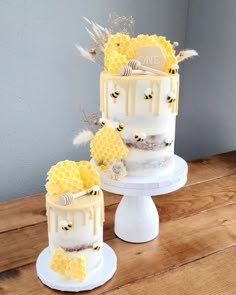 three tiered cake with honeycombs and bees on the top, sitting on a wooden table