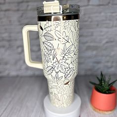 a white blender sitting on top of a table next to a potted plant